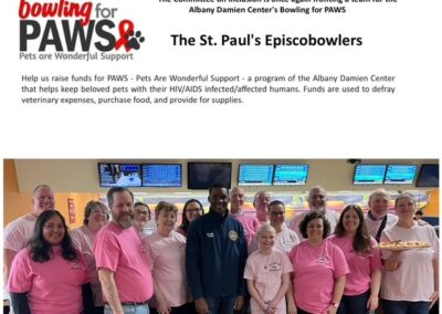 Group of people in pink shirts pose at bowling alley for PAWS charity event, supporting pets of those affected by HIV/AIDS.
